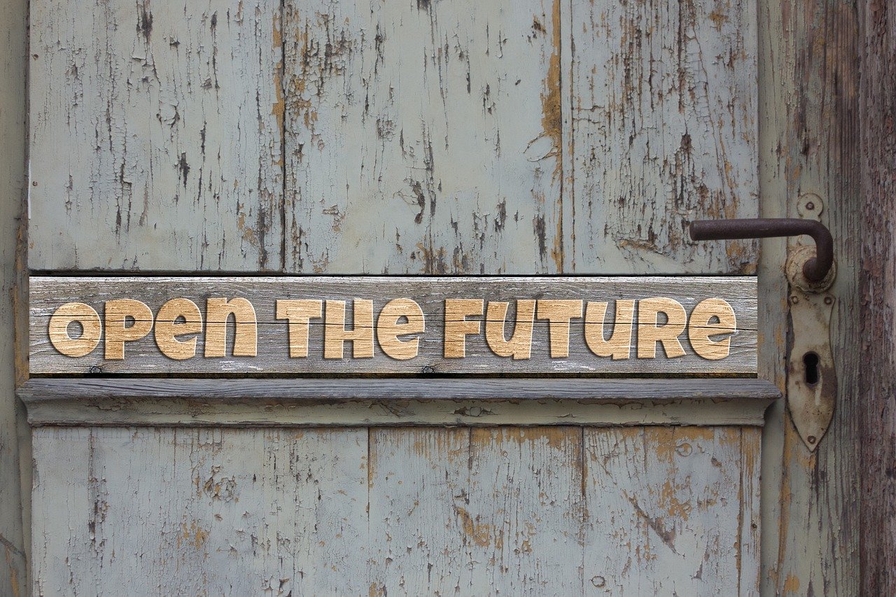 Porta in legno con scritta Open the Future, simbolo di apertura al futuro e al cambiamento